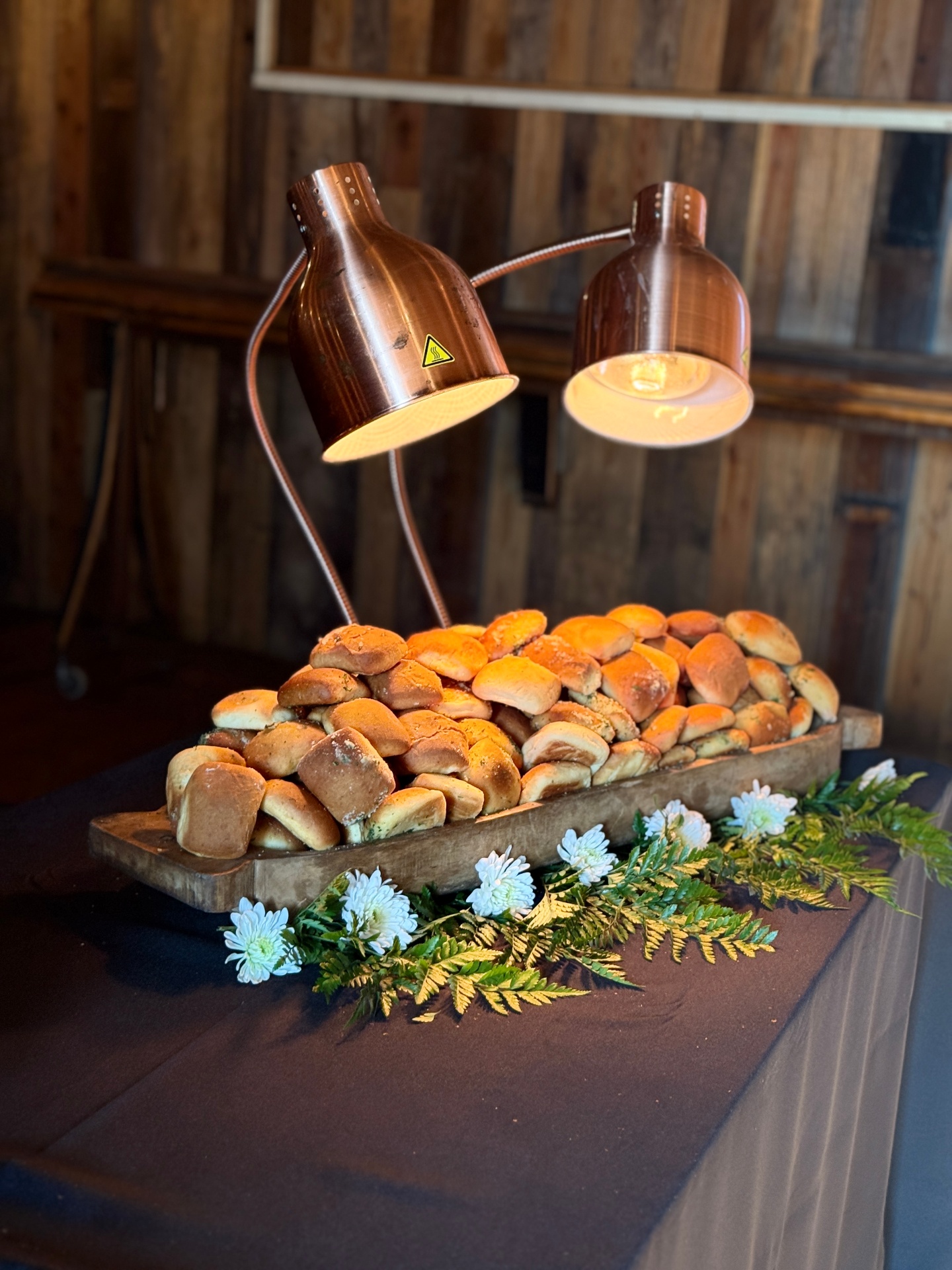 Fresh-baked rolls under copper warming lamps at a White Wine & Butter catering event